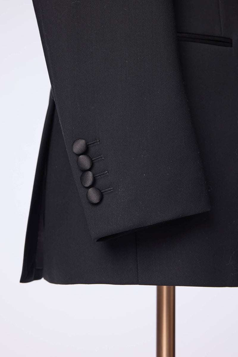 Luxury black fabric texture with custom sleeve buttons on bespoke peak lapel tuxedo