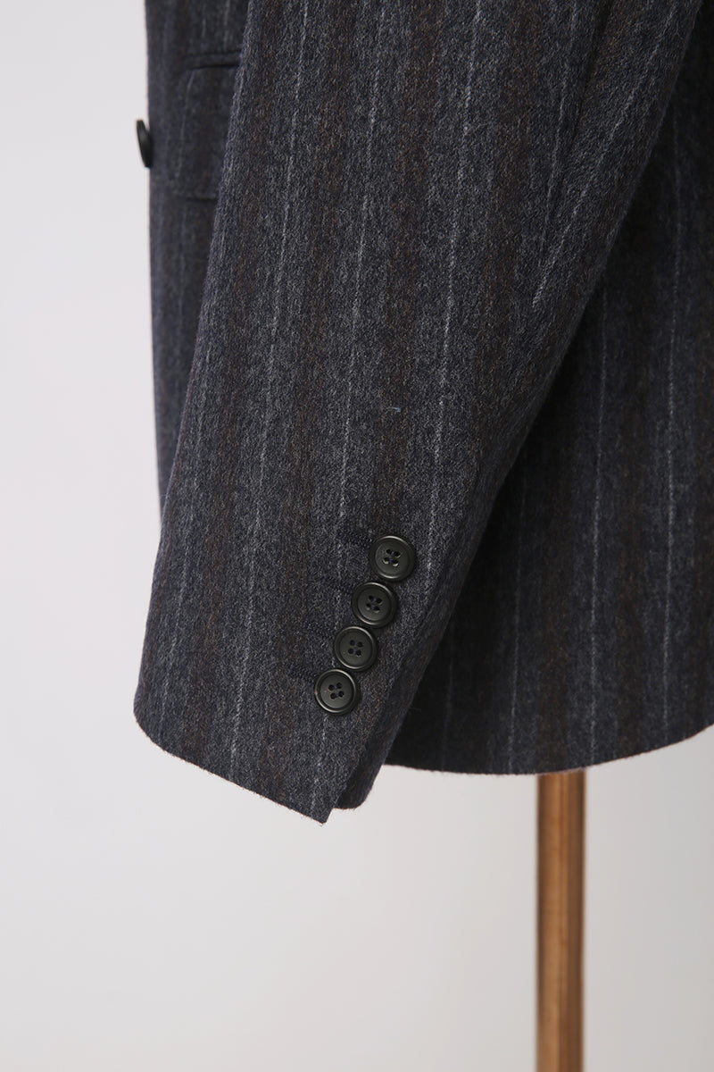 Custom sleeve buttons on tailored charcoal pinstripe blazer