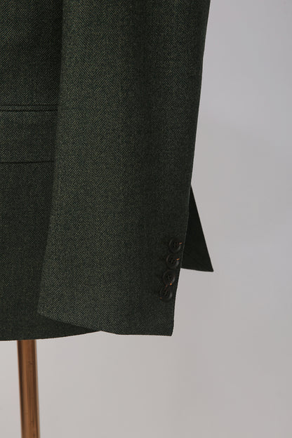 Luxury herringbone fabric texture on bespoke dark green men’s blazer close up on sleeve buttons