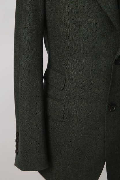 Custom sleeve buttons on tailored dark green herringbone blazer with ticket pocket