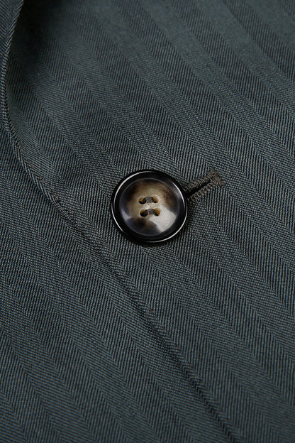 Custom jacket button on tailored forest green herringbone suit